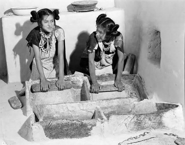 Two young women performing the Corn Grinding Ceremony